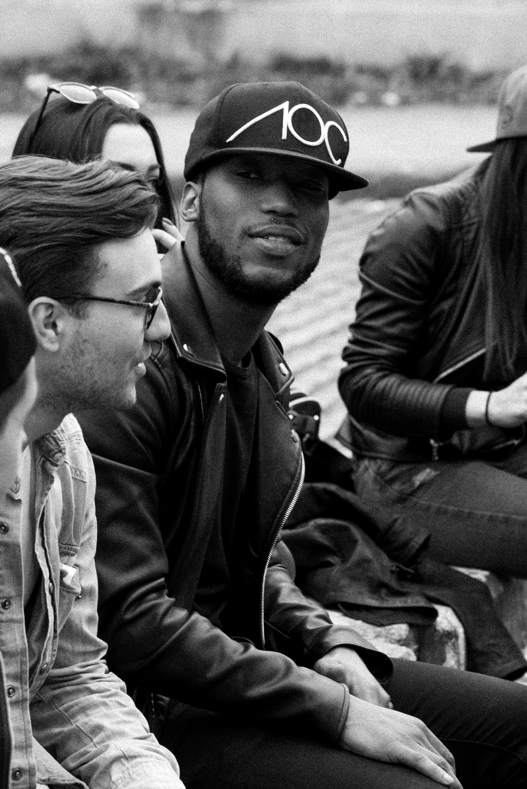 Two AOC crew members in branded caps laughing together on a Shoreditch street