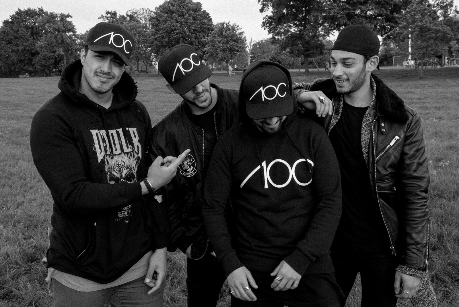 Group of AOC crew members with arms around each other, laughing outdoors in branded hoodies