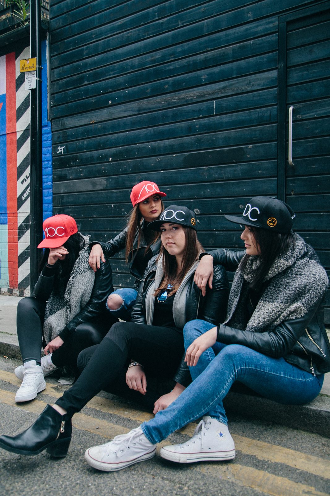 Three AOC crew members sitting together casually on a Shoreditch curb, chatting